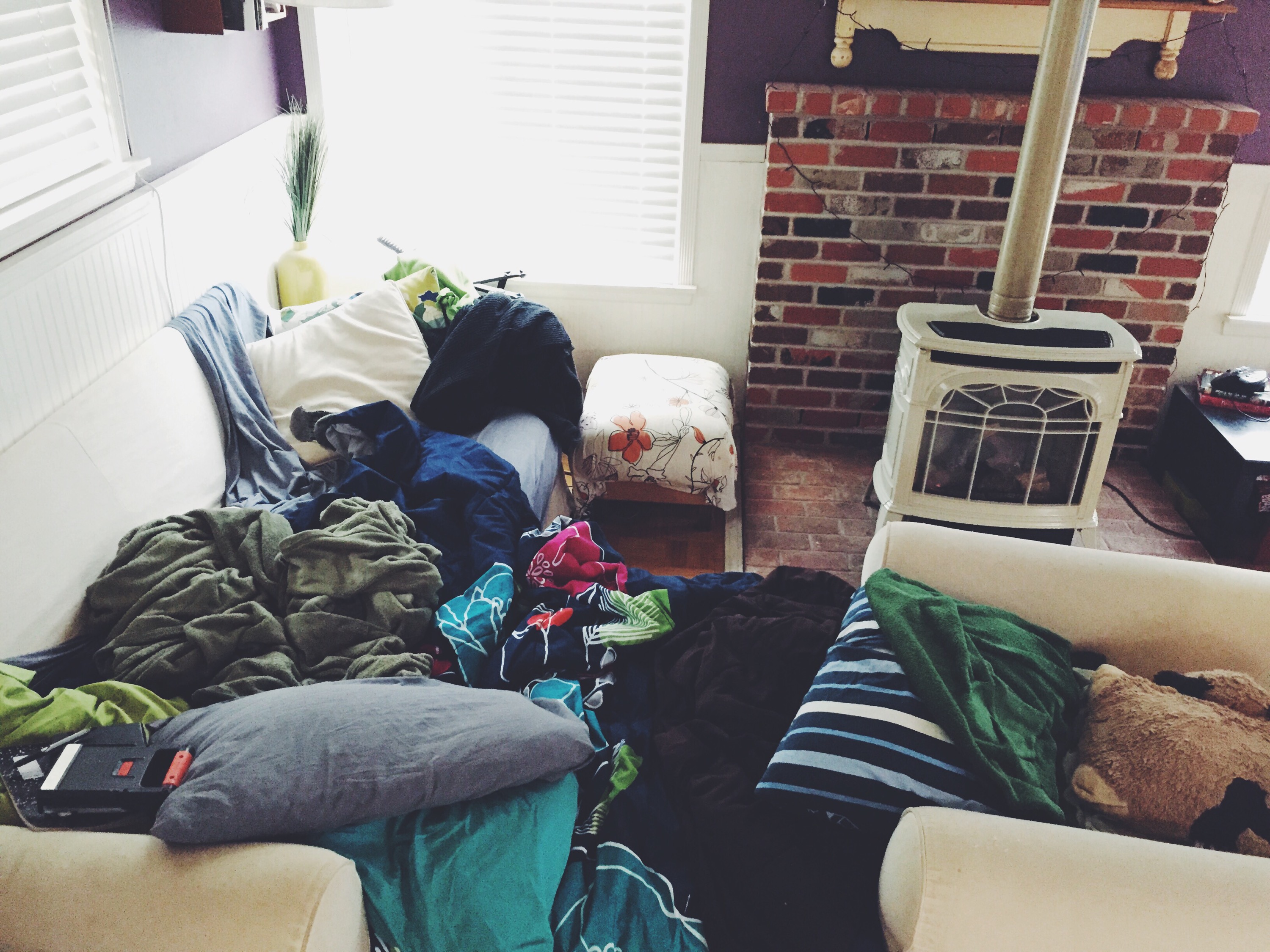 chaise and couch pushed together covered in blankets and pillows